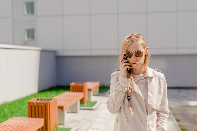 Jonge vrouw met een smartphone tegen de muur.