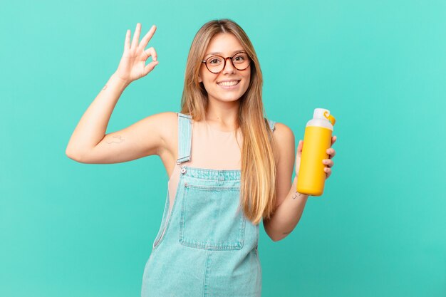 Jonge vrouw met een smoothy gevoel gelukkig, goedkeuring tonend met een goed gebaar