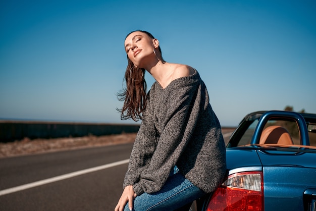 Jonge vrouw met een staart die buiten in de buurt van een auto zonder dak staat