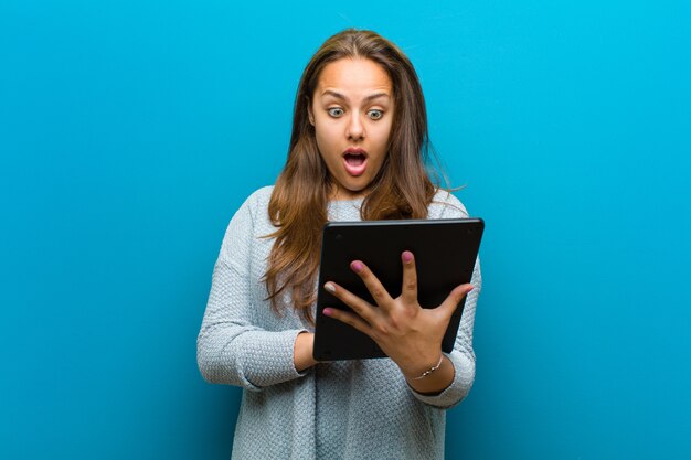 Jonge vrouw met een tablet blauwe muur