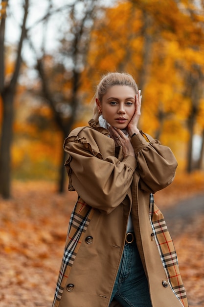 jonge vrouw met een trendy kapsel in een elegante jas vormt buiten in een park