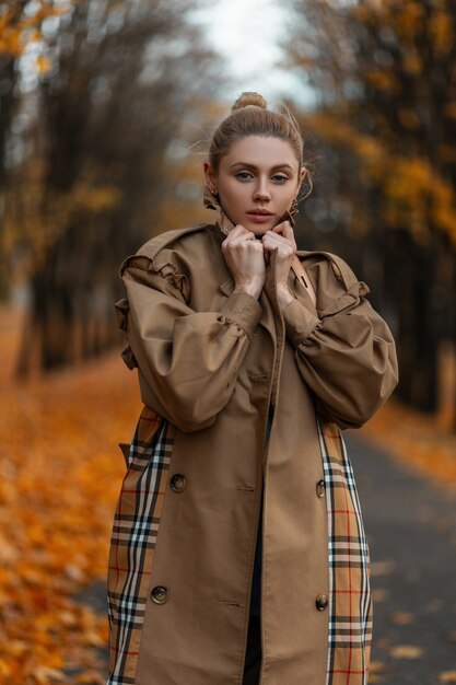 jonge vrouw met een trendy kapsel in een elegante jas vormt buiten in een park