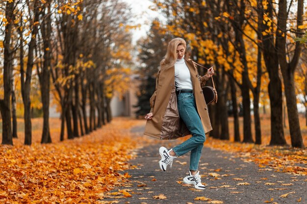 jonge vrouw met een trendy kapsel in een elegante jas vormt buiten in een park