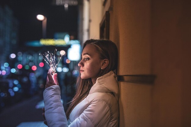 Jonge vrouw met een verlichte snaarlamp's nachts