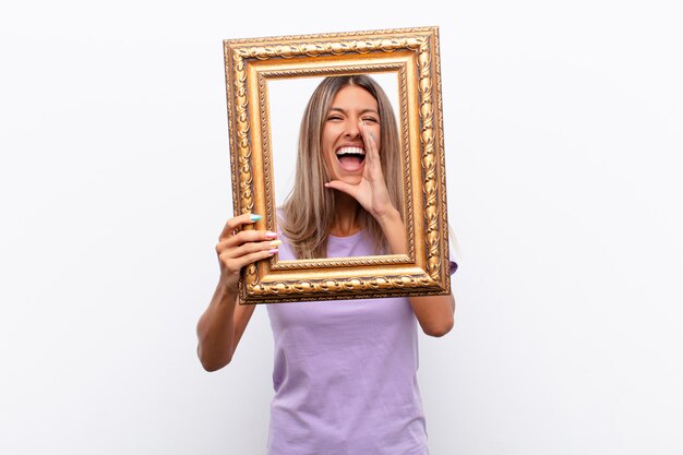 Jonge vrouw met een vrolijke, zorgeloze, rebelse houding, grapjes maken en tong uitsteken, plezier maken met een barok frame.