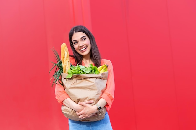 jonge vrouw met een winkelzak vol groente boodschappen jonge vrouw met boodschappen papier winkelzak vol verse groenten vrouw met een boodschappenzak vol vers voedsel