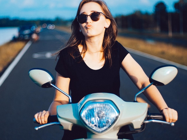 Jonge vrouw met een zonnebril die op een scooter rijdt