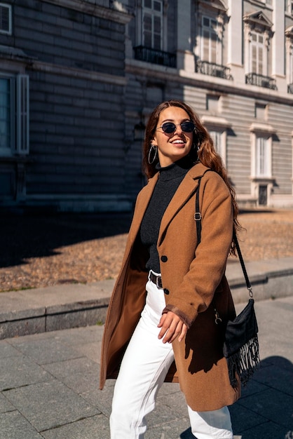 Jonge vrouw met een zonnebril die op straat staat in de stad