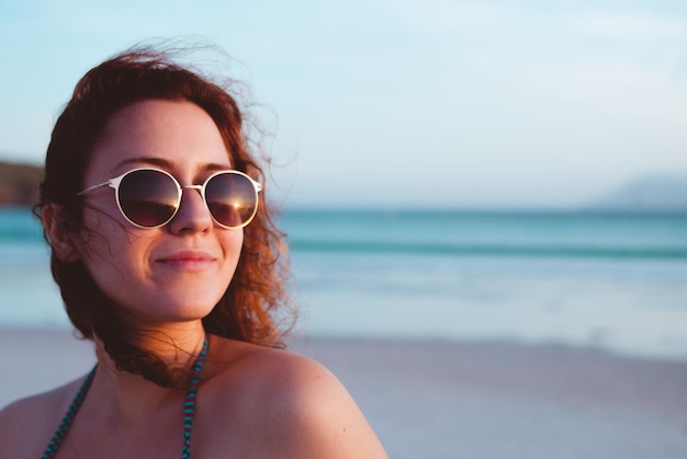 Jonge vrouw met een zonnebril op het strand