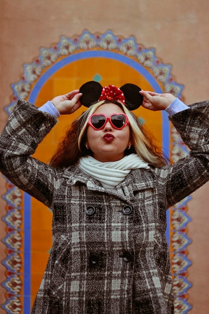 Foto jonge vrouw met een zonnebril tegen de muur.