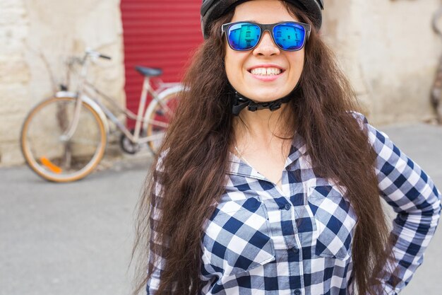 Foto jonge vrouw met een zonnebril terwijl ze tegen de muur staat