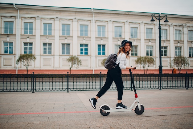 Jonge vrouw met elektrische autoped bij de stad