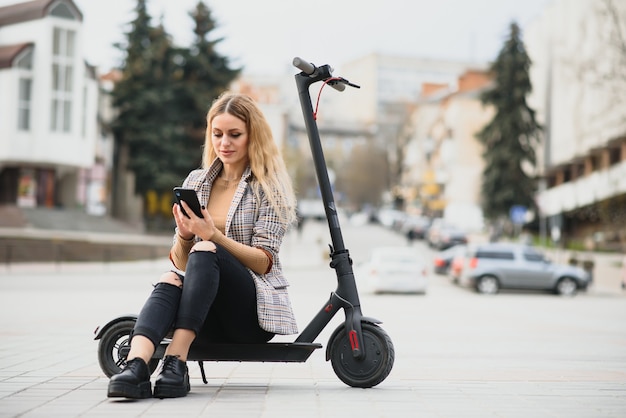 Jonge vrouw met elektrische autoped in de stad