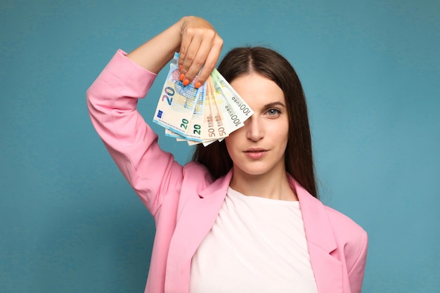 jonge vrouw met eurobiljetten in de buurt van haar gezicht