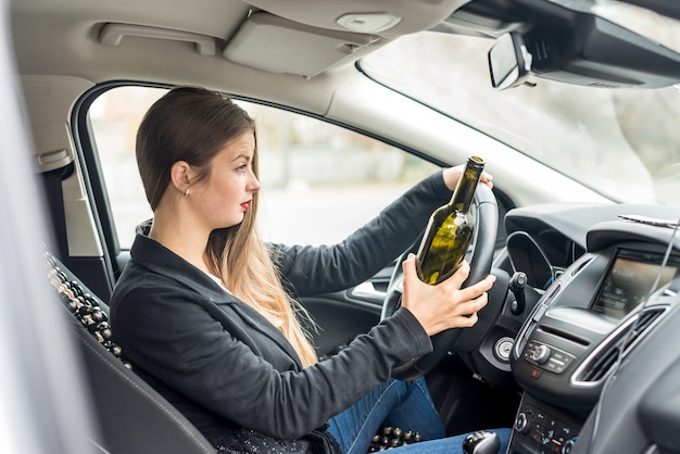 Jonge vrouw met fles autorijden