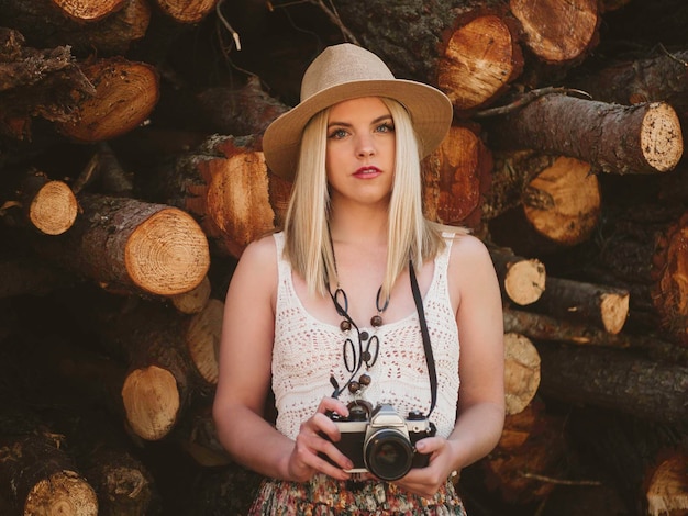 Foto jonge vrouw met fotocamera in park met log od hout
