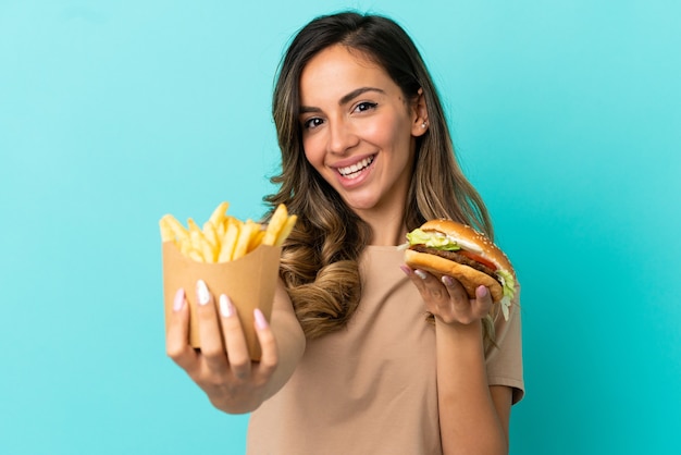 Jonge vrouw met gebakken chips en hamburger over geïsoleerde achtergrond