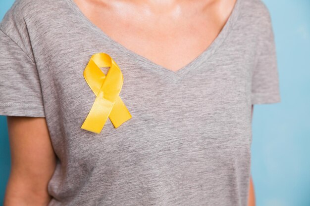 Jonge vrouw met geel gouden lint bewustzijn symbool voor endometriose zelfmoord preventie sarcoom botkanker blaaskanker leverkanker en kinderkanker concept Gezondheidszorg Close-up