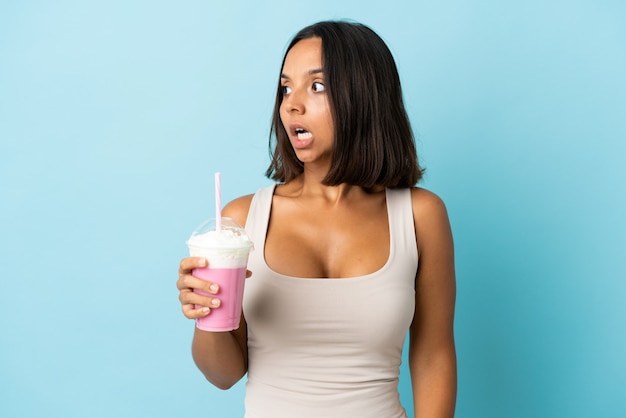 Jonge vrouw met geïsoleerde aardbeimilkshake