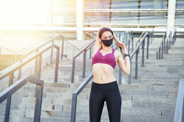 Jonge vrouw met gesloten ogen en beschermend masker die hand uitrekken doet. Sportconcept. Ruimte kopiëren