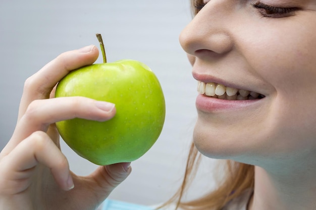 Jonge vrouw met gezonde tand die groene appel bijt