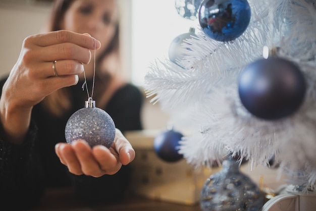 Jonge vrouw met glanzende blauwe kerstbal in haar handen