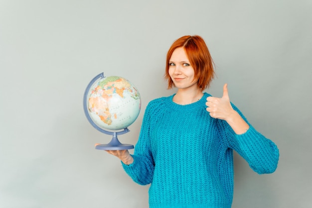 Foto jonge vrouw met glode geïsoleerd op de grijze achtergrond met thumbs up