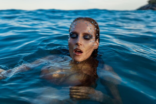 Foto jonge vrouw met gouden huid in het water.