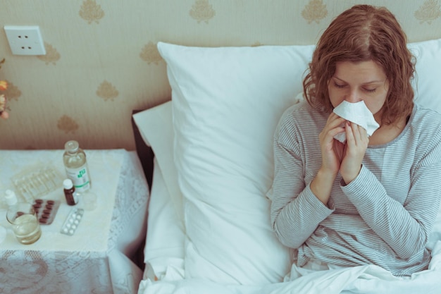 Jonge vrouw met griep en hoge koorts in bed.