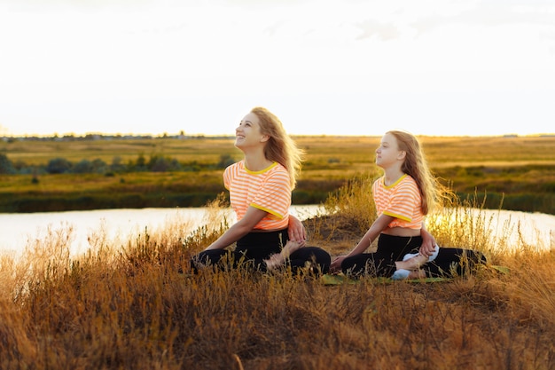 Jonge vrouw met haar dochter die yoga buiten maakt