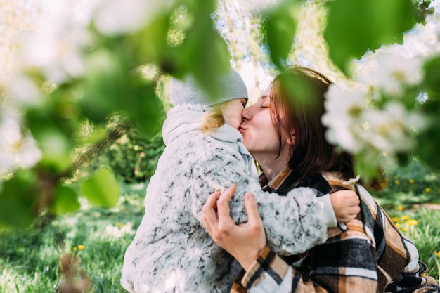 Jonge vrouw met haar dochter in de natuur bewondert de witte bloei van voorjaarsbomen