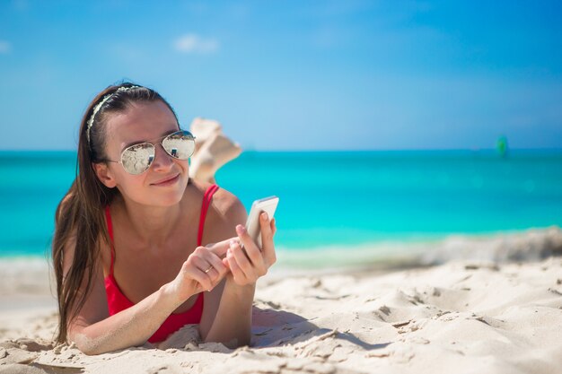 Jonge vrouw met haar mobiele telefoon op exotisch strand