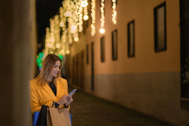 Jonge vrouw met haar smartphone boodschappen doen tijdens de kerstperiode