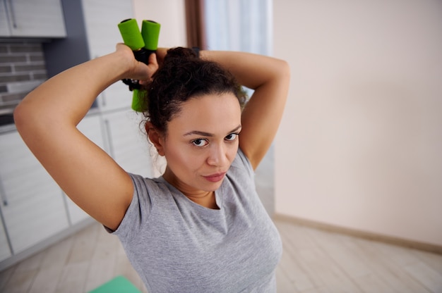 Jonge vrouw met halters en haar triceps pompen zittend op een fitness-bal. Thuis training concept