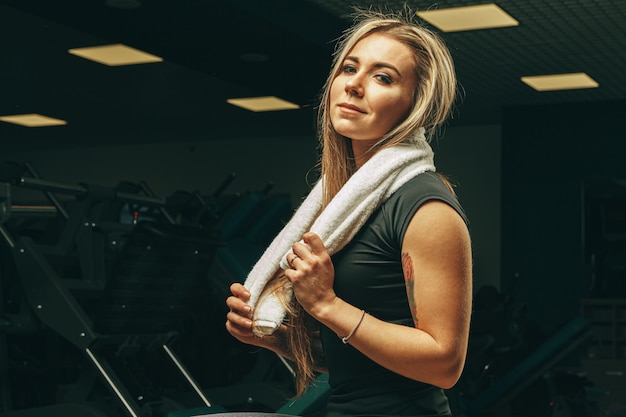 Jonge vrouw met handdoekzitting en het rusten in een gymnastiek