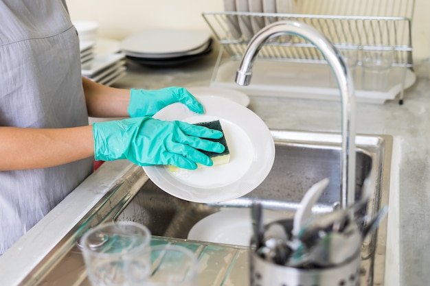 Jonge vrouw met handschoenen afwas