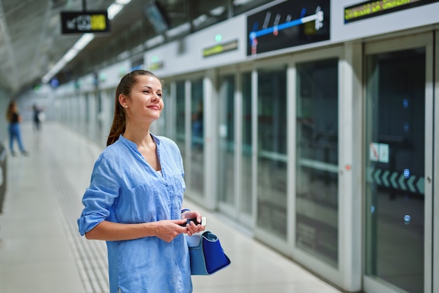 Jonge vrouw met handtas in metrostation.