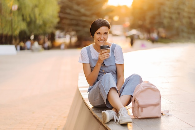 Jonge vrouw met herbruikbare koffiekopje bij zonsondergang. Duurzame levensstijl. Kunststofvrij concept.