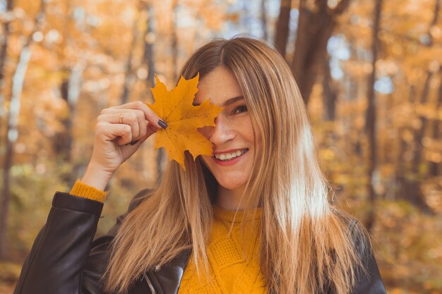 Jonge vrouw met herfst oranje esdoornblad over herfst seizoen achtergrond
