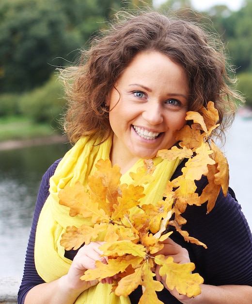 Jonge vrouw met herfstbladeren in park