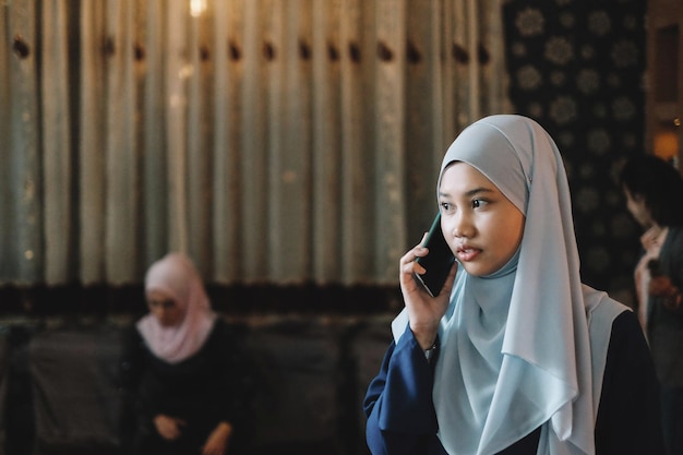 Jonge vrouw met hijab die aan het bellen is.