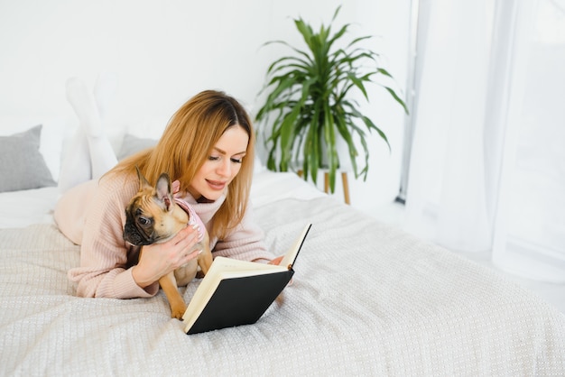 Jonge vrouw met hond en boek thuis ontspannen thuis, lezen.