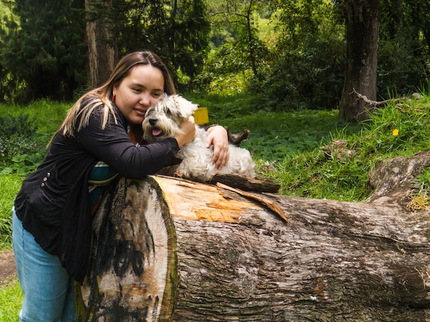 Jonge vrouw met hond op boomstam