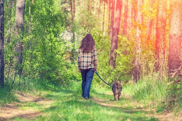 Jonge vrouw met hond wandelen in het bos bij zonsondergang