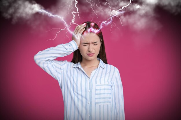 Foto jonge vrouw met hoofdpijn op roze achtergrond illustratie van bliksemschichten die hevige pijn vertegenwoordigen