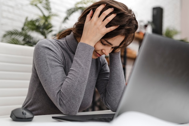 Foto jonge vrouw met hoofdpijn tijdens het werken vanuit huis