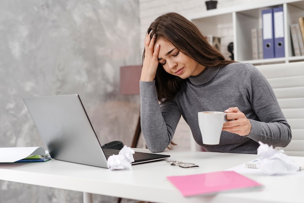 Foto jonge vrouw met hoofdpijn tijdens het werken vanuit huis