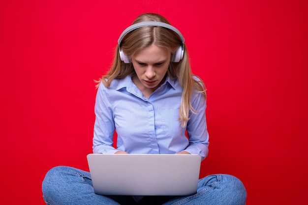 Jonge vrouw met hoofdtelefoons die op laptop typen
