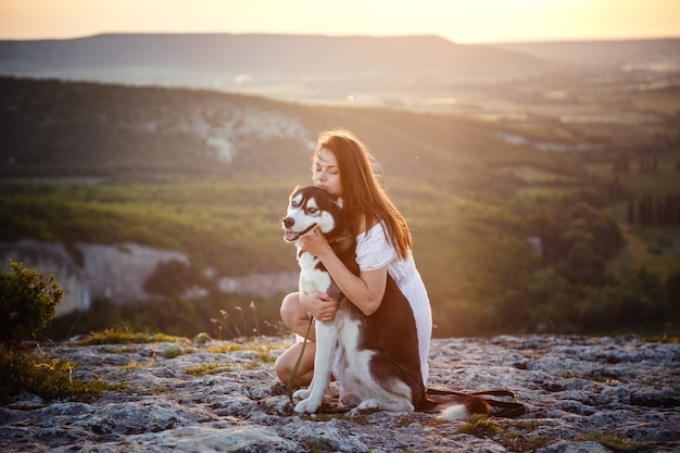 Jonge vrouw met Husky hond op een zonnige dag zitten in het hooggebergte