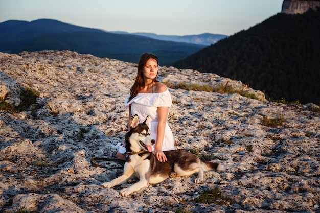 Jonge vrouw met husky hond op een zonnige dag zitten in het hooggebergte